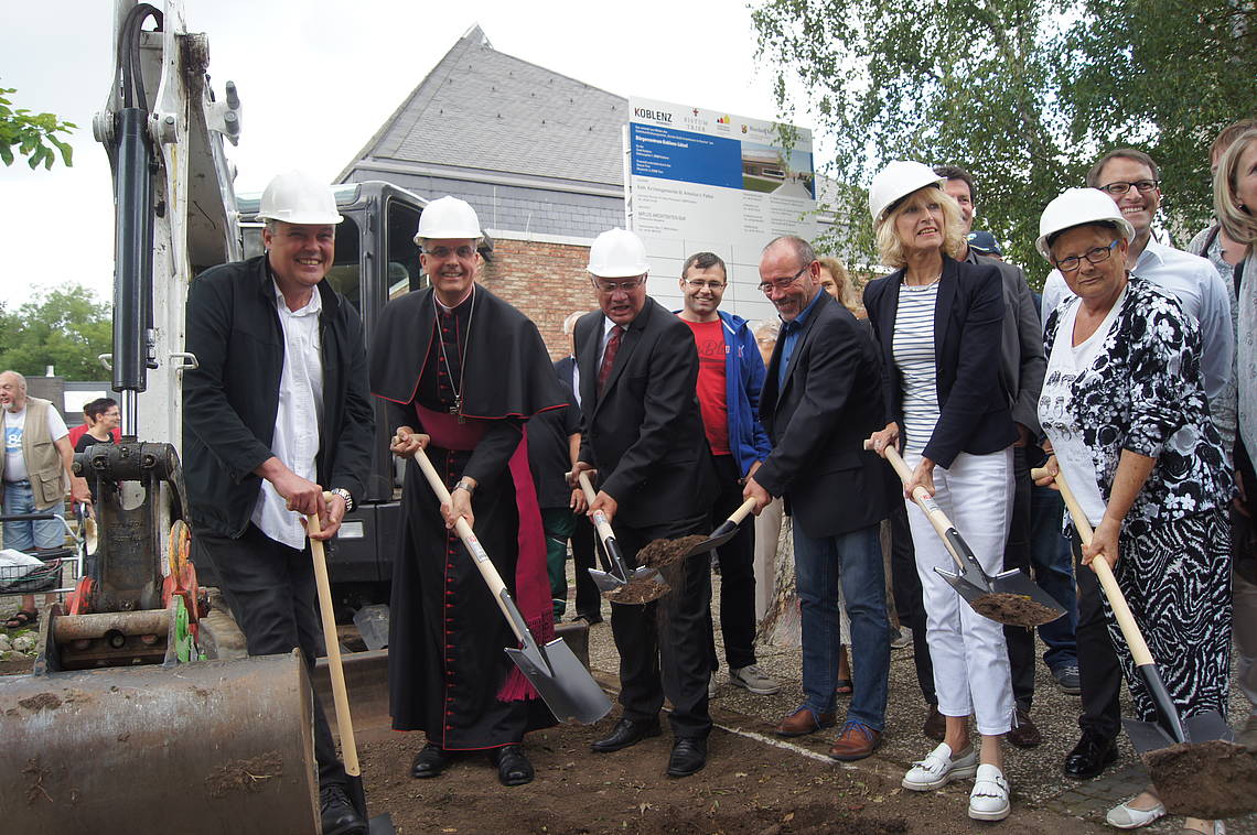 Menschen mit einem Spaten in der Hand stehen zusammen und eröffnen die Baustelle am Bürgerzentrum