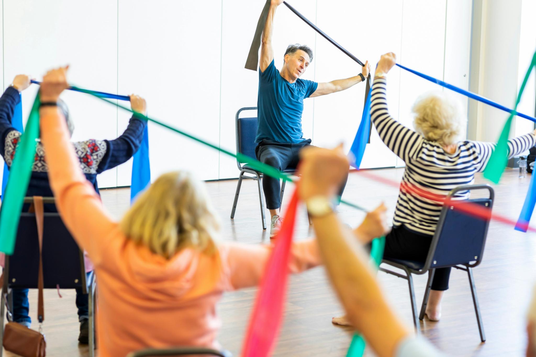 Ältere Menschen bei Dehnungsübungen mit Gymnastikbändern